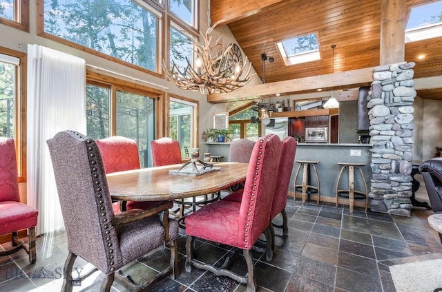 953 Angel Point Rd, Lakeside, MT 59922 - dining area with high vaulted ceiling, stone tile flooring, a skylight, a chandelier, and healthy amount of natural light
