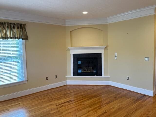 unfurnished living room featuring ornamental molding and light hardwood / wood-style flooring