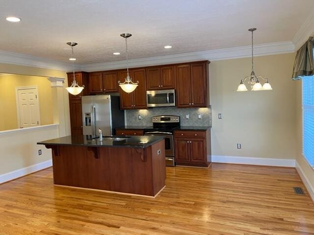 kitchen with decorative light fixtures, light hardwood / wood-style floors, a center island with sink, a kitchen bar, and stainless steel appliances