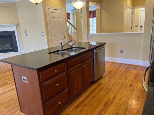 kitchen featuring light hardwood / wood-style flooring, stainless steel dishwasher, sink, and an island with sink