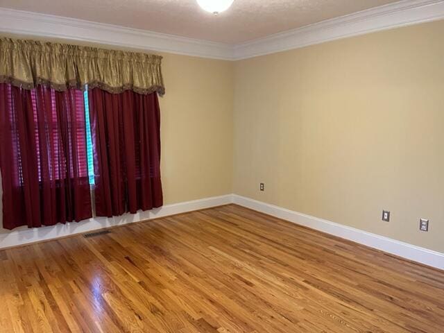 empty room featuring crown molding and light wood-type flooring