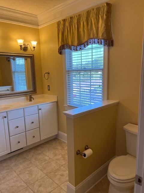 bathroom featuring toilet, ornamental molding, tile floors, and vanity