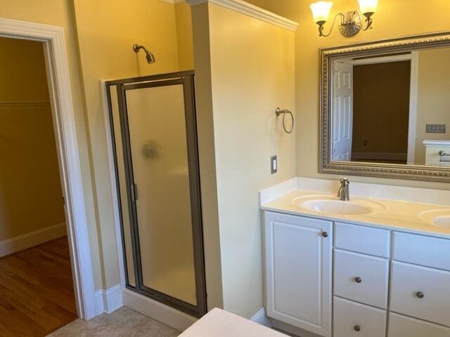 bathroom with a shower with shower door, dual bowl vanity, and hardwood / wood-style flooring