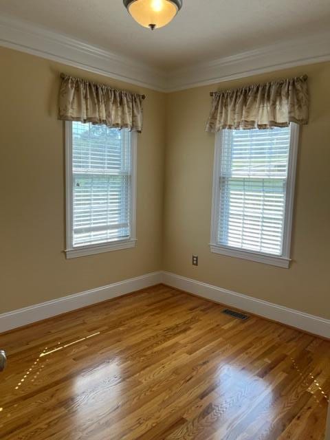 spare room featuring crown molding and light hardwood / wood-style floors