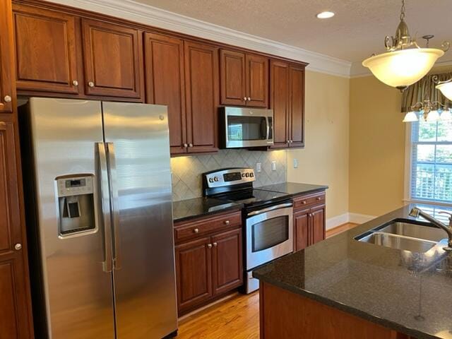 kitchen featuring a chandelier, pendant lighting, stainless steel appliances, tasteful backsplash, and light wood-type flooring