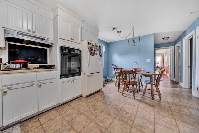 kitchen featuring light tile floors, white fridge, black oven, white cabinets, and an inviting chandelier