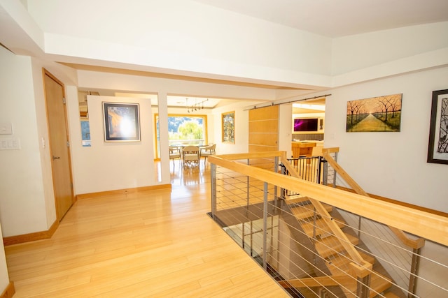 hallway with an inviting chandelier and light hardwood / wood-style floors