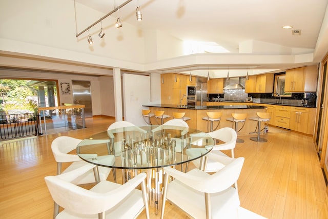 dining room featuring high vaulted ceiling, light wood-type flooring, and rail lighting