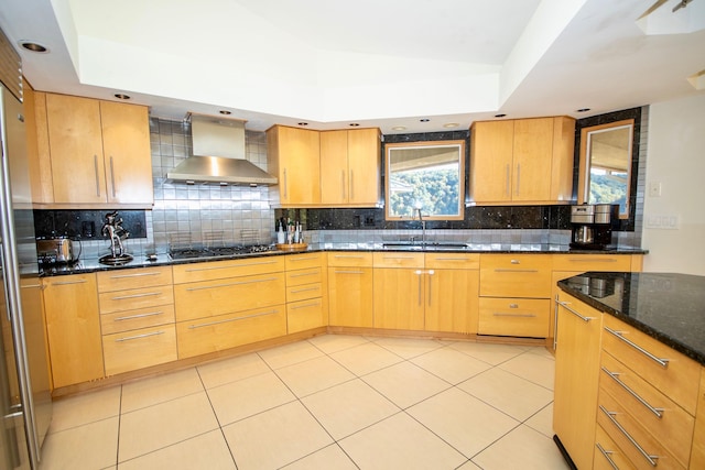 kitchen with dark stone counters, backsplash, plenty of natural light, and wall chimney exhaust hood