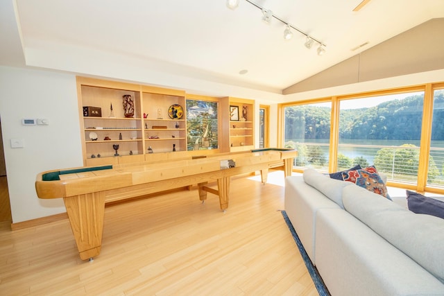 game room with lofted ceiling, a water view, light hardwood / wood-style floors, and rail lighting