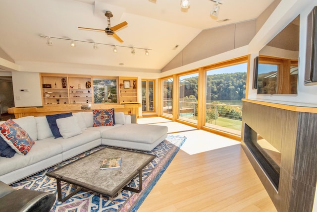 living room with ceiling fan, track lighting, light wood-type flooring, and vaulted ceiling