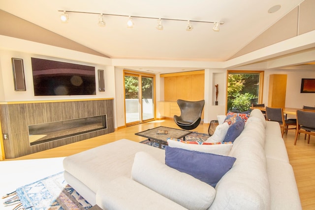 living room with rail lighting, vaulted ceiling, and light wood-type flooring