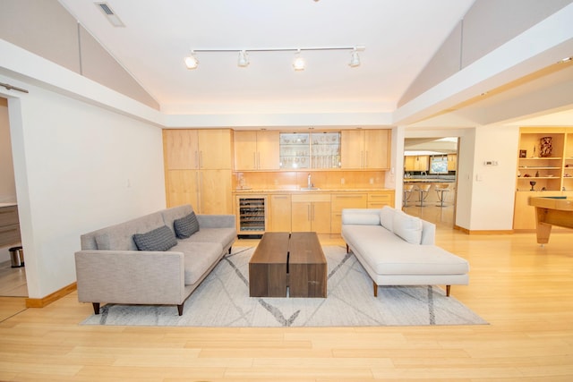 living room with track lighting, high vaulted ceiling, light hardwood / wood-style floors, and wine cooler