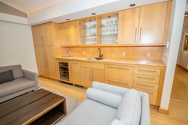 interior space featuring light brown cabinetry, tasteful backsplash, light hardwood / wood-style floors, beverage cooler, and sink