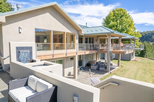 rear view of property with outdoor lounge area, a patio, a yard, and a balcony