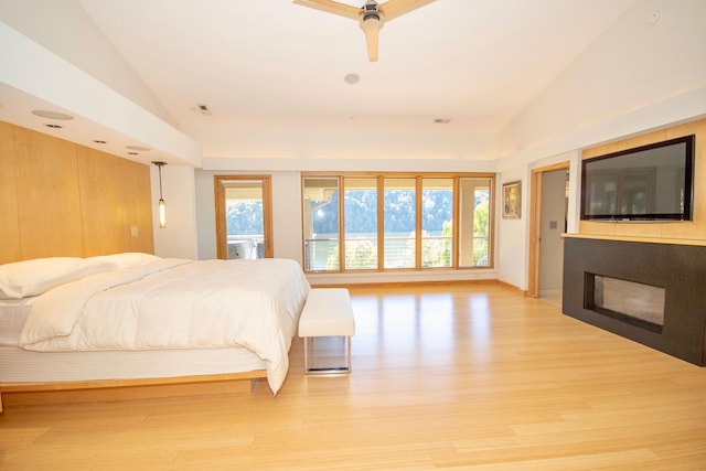 bedroom with lofted ceiling, light wood-type flooring, and multiple windows