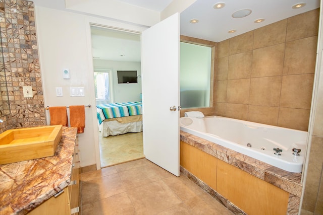 bathroom with tile floors, vanity, and a bath to relax in