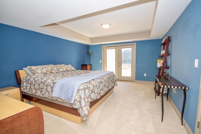 carpeted bedroom with french doors, access to exterior, and a tray ceiling