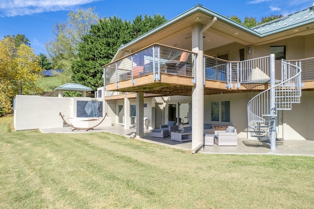 rear view of house with a balcony, an outdoor living space, a patio area, and a lawn