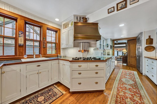 kitchen with white cabinets, sink, appliances with stainless steel finishes, and light hardwood / wood-style floors