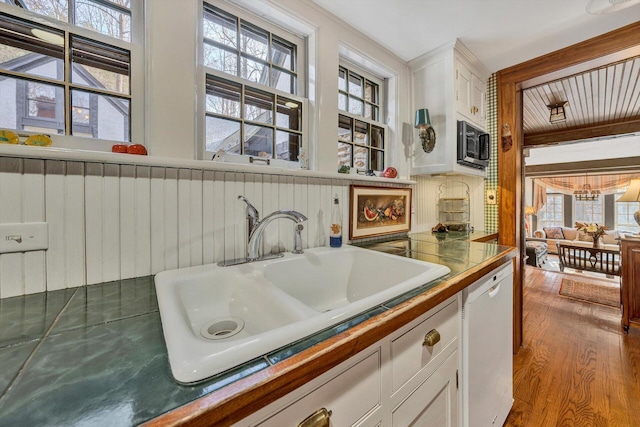 kitchen with tasteful backsplash, white cabinets, hardwood / wood-style floors, sink, and white dishwasher