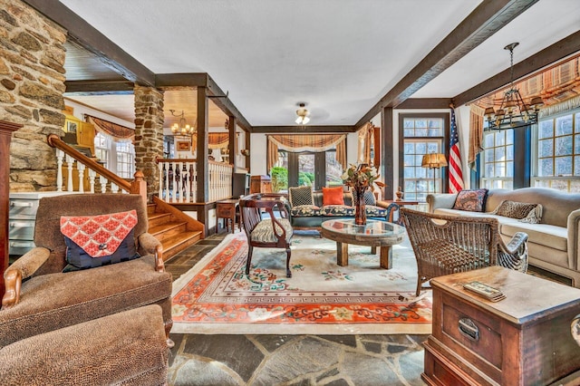 living room featuring beam ceiling, a chandelier, and ornate columns