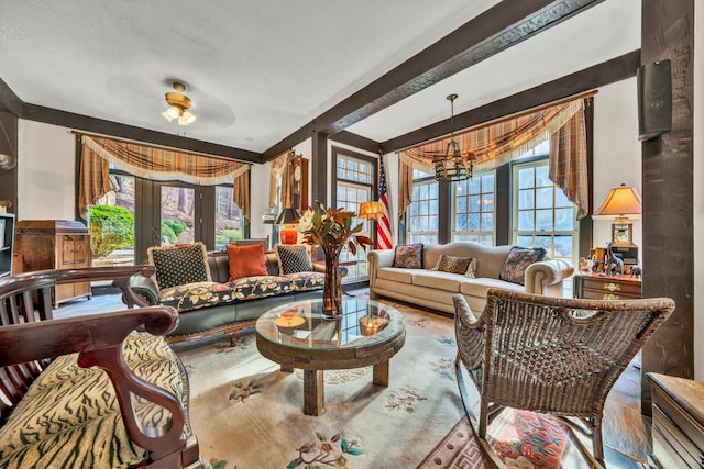 living room with french doors, ceiling fan with notable chandelier, and beamed ceiling