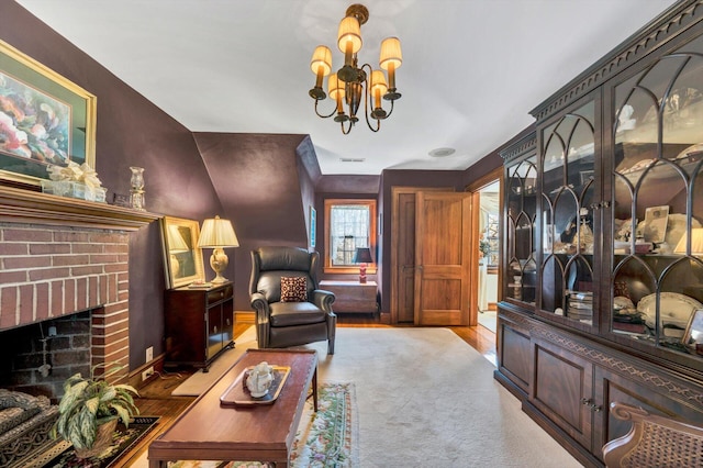 living room with an inviting chandelier, a fireplace, and light wood-type flooring