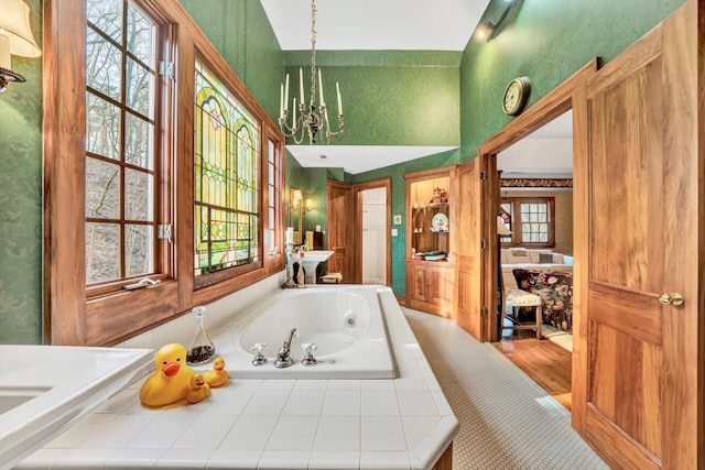 bathroom with an inviting chandelier, hardwood / wood-style floors, and a washtub