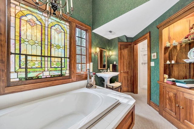 bathroom with a notable chandelier, a bathing tub, and sink