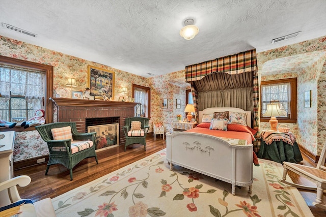 bedroom featuring a textured ceiling, a fireplace, dark wood-type flooring, and multiple windows