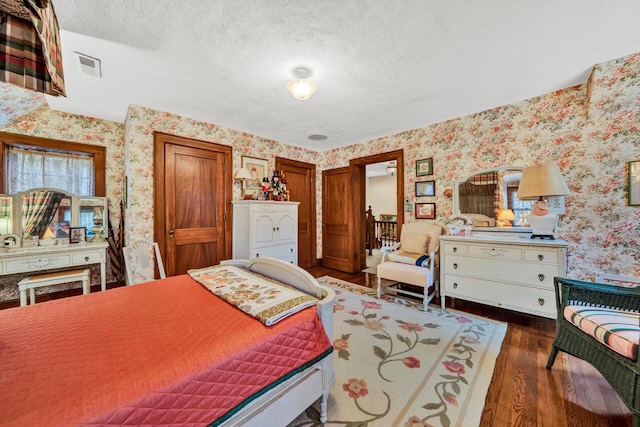 bedroom with a textured ceiling and dark wood-type flooring