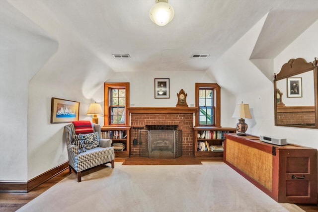 living area featuring dark hardwood / wood-style floors, vaulted ceiling, and a brick fireplace