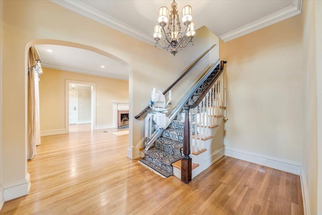 stairway with crown molding, a chandelier, and light hardwood / wood-style floors