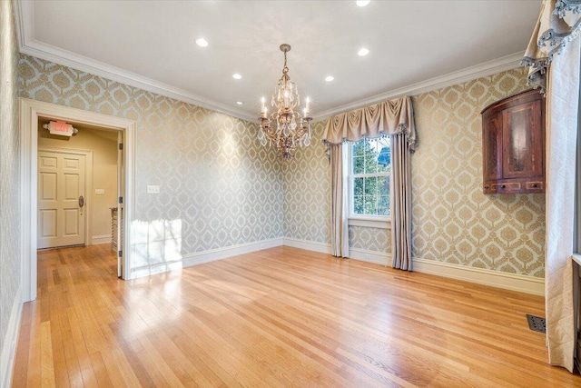 spare room featuring a notable chandelier, crown molding, and light hardwood / wood-style floors