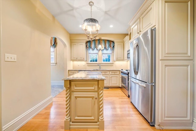 kitchen featuring pendant lighting, stainless steel appliances, a center island, light hardwood / wood-style flooring, and an inviting chandelier