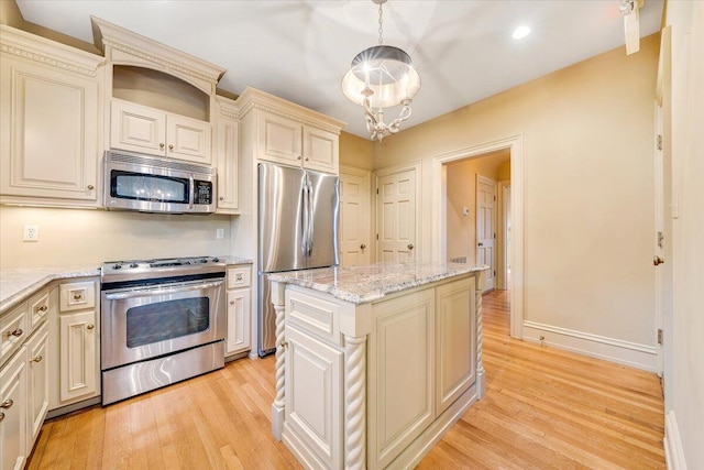 kitchen featuring pendant lighting, cream cabinetry, light hardwood / wood-style flooring, and appliances with stainless steel finishes