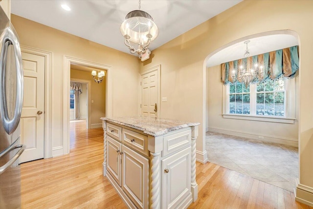 kitchen with a notable chandelier, hanging light fixtures, a kitchen island, and light hardwood / wood-style flooring