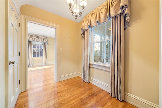 empty room featuring a chandelier and light hardwood / wood-style floors