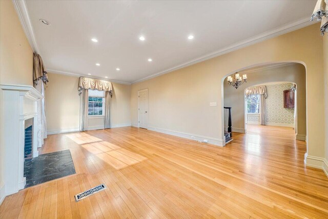 unfurnished living room with ornamental molding, a chandelier, and light wood-type flooring