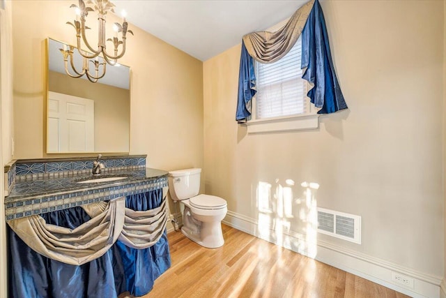 bathroom featuring toilet, hardwood / wood-style floors, a notable chandelier, and vanity