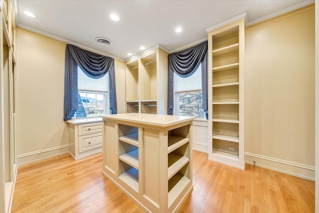 spacious closet with built in desk and light hardwood / wood-style flooring