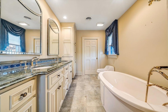 bathroom featuring toilet, tile flooring, a bathing tub, and vanity