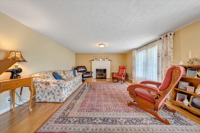 living room featuring a fireplace, a textured ceiling, and light wood-type flooring