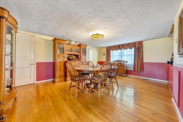 dining area with light wood-type flooring and a textured ceiling