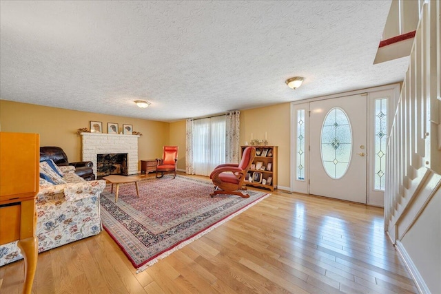 living room featuring light hardwood / wood-style flooring, a wealth of natural light, a fireplace, and a textured ceiling