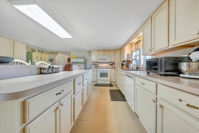 kitchen with white appliances, cream cabinetry, and sink