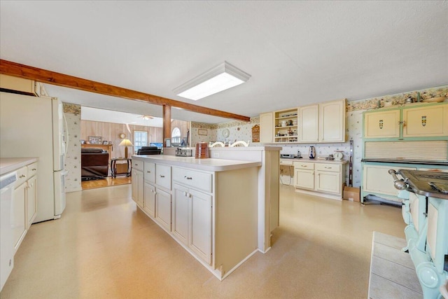 kitchen featuring cream cabinetry, a textured ceiling, white fridge, and a center island