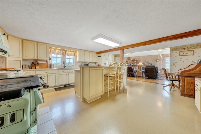 kitchen with sink, a breakfast bar area, range, white fridge with ice dispenser, and a textured ceiling