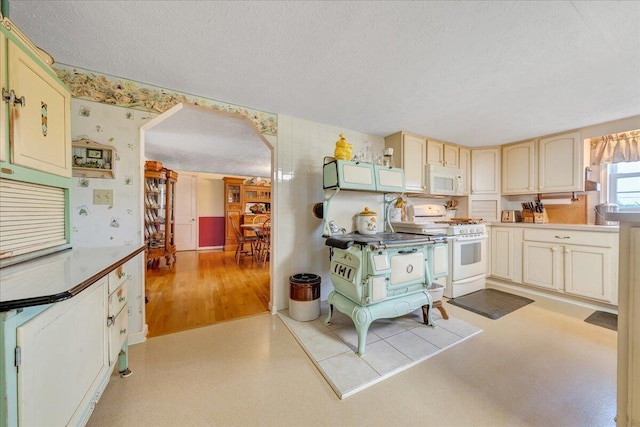 kitchen with white appliances, a textured ceiling, and light hardwood / wood-style flooring